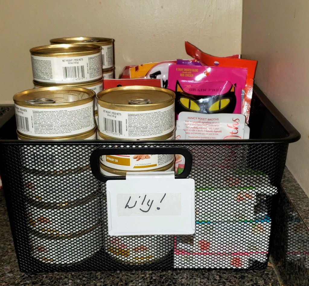 A black metal basket with cat food and treats in it